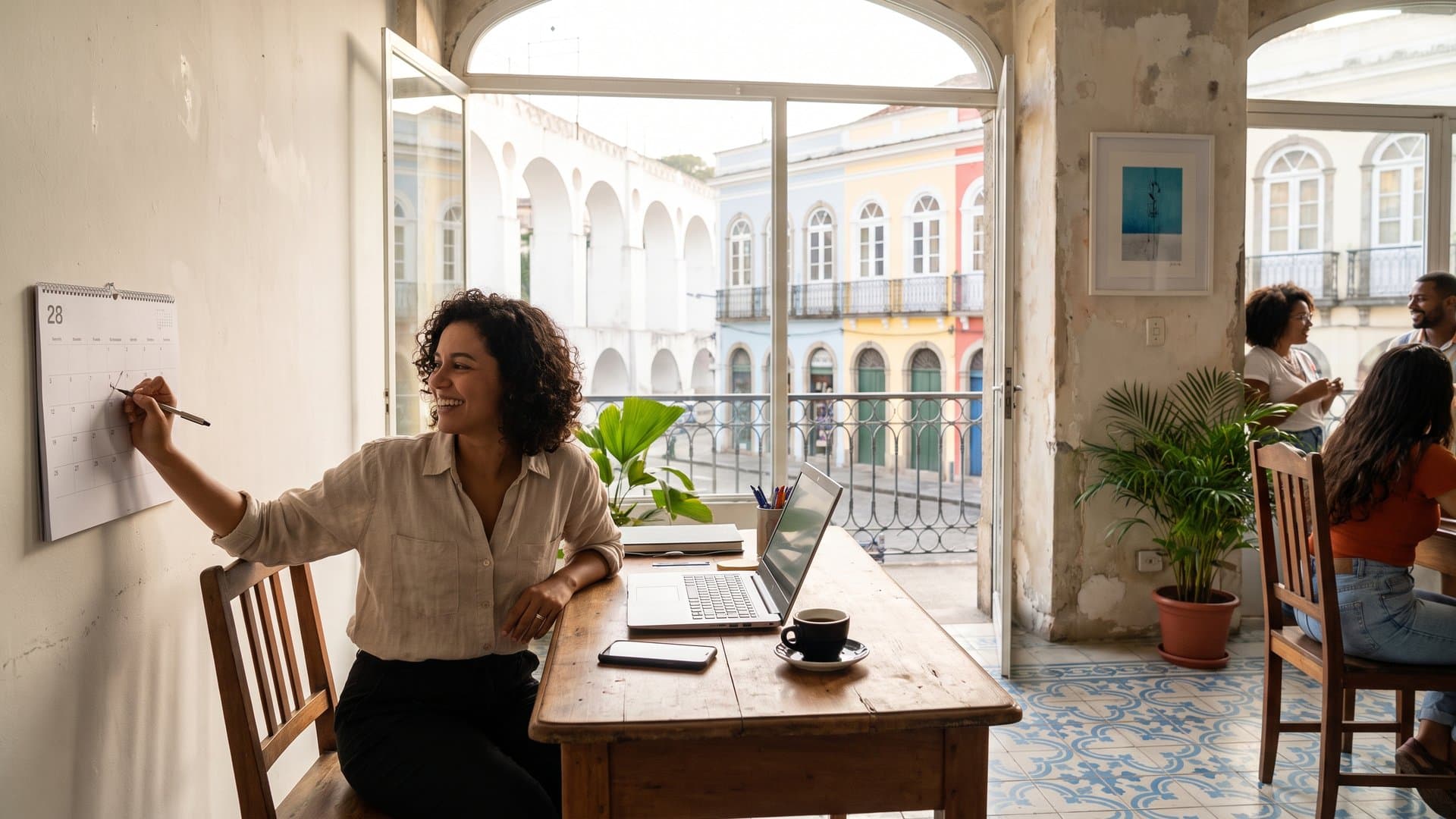 Escritório pequeno e organizado com notebook, calendário de parede e telefone